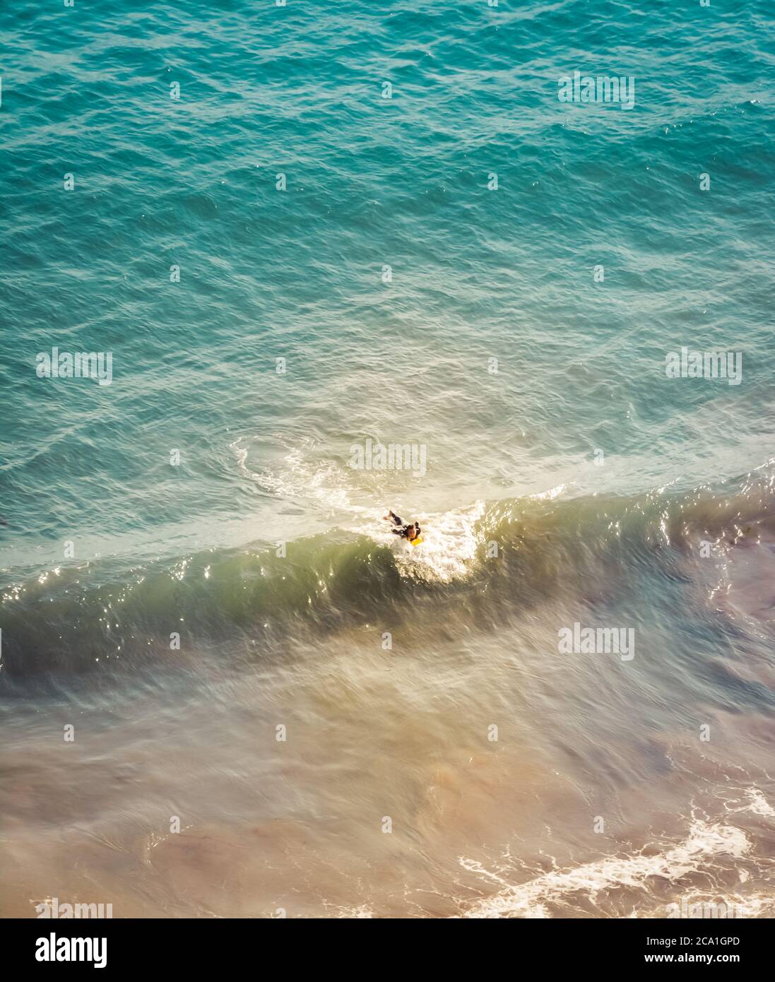 A downward view of a lone surfer attempting to catch a small wave in the Pacific Ocean near Santa Barbara, CA, USA Stock Photo
