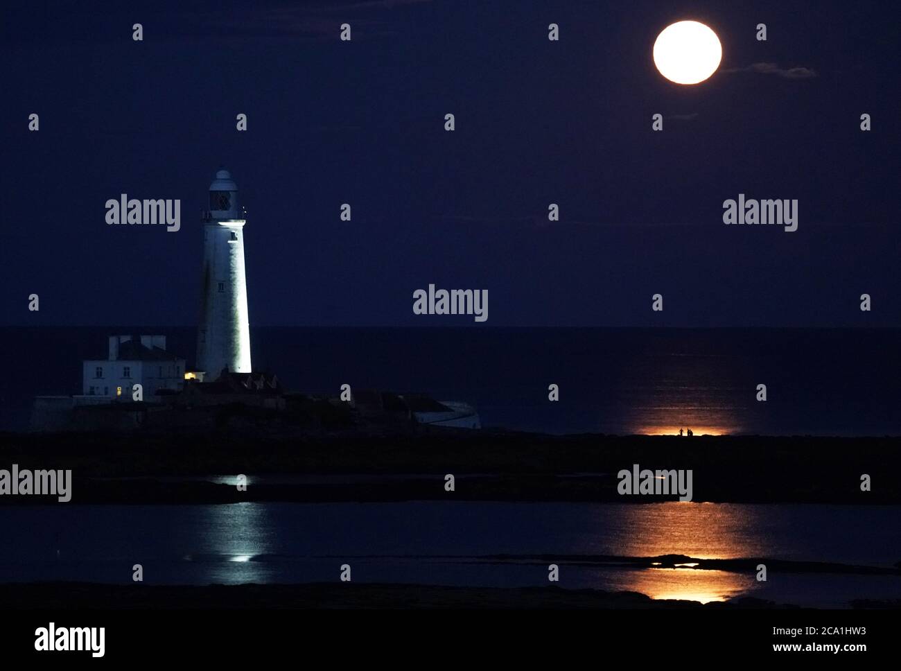 The August Full Moon, known as the Sturgeon Moon, rises above St Mary's Lighthouse in Whitley Bay. Stock Photo