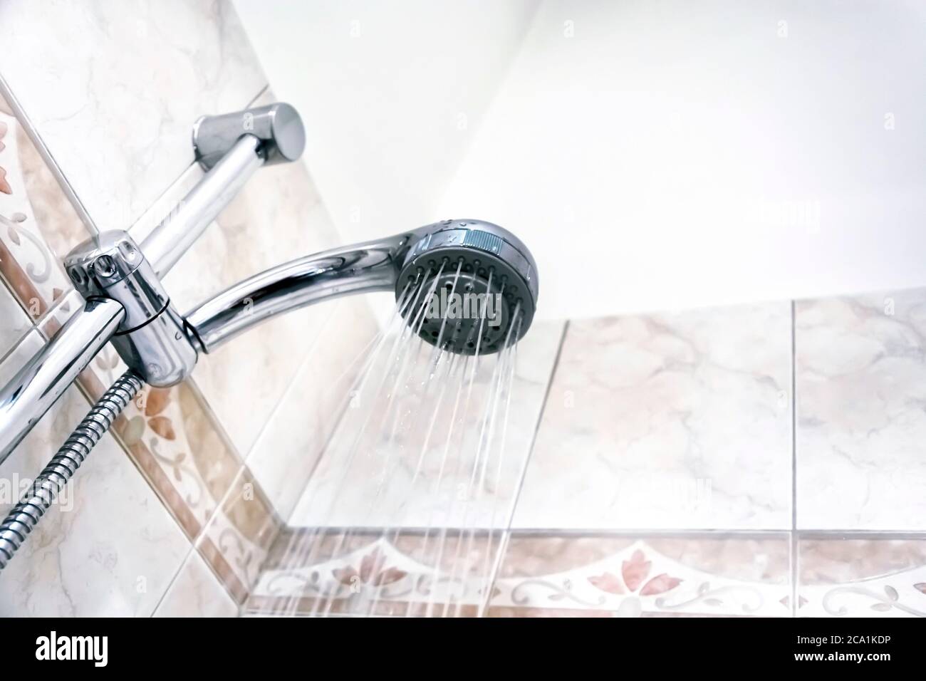 Interior of a shower with water flowing from the shower head. Droplets