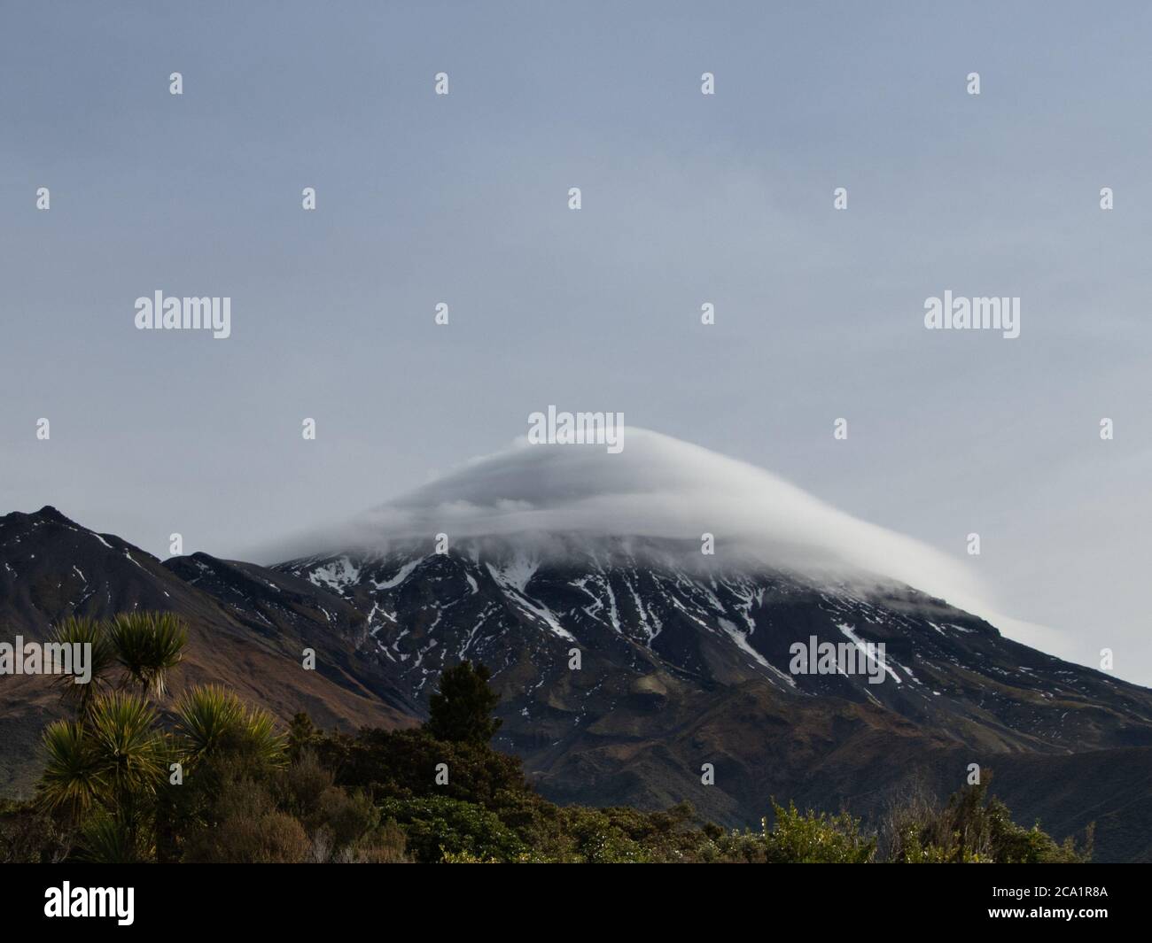 Mount Taranaki New Zealand with trees and cloud cap on cloudy day close up Stock Photo