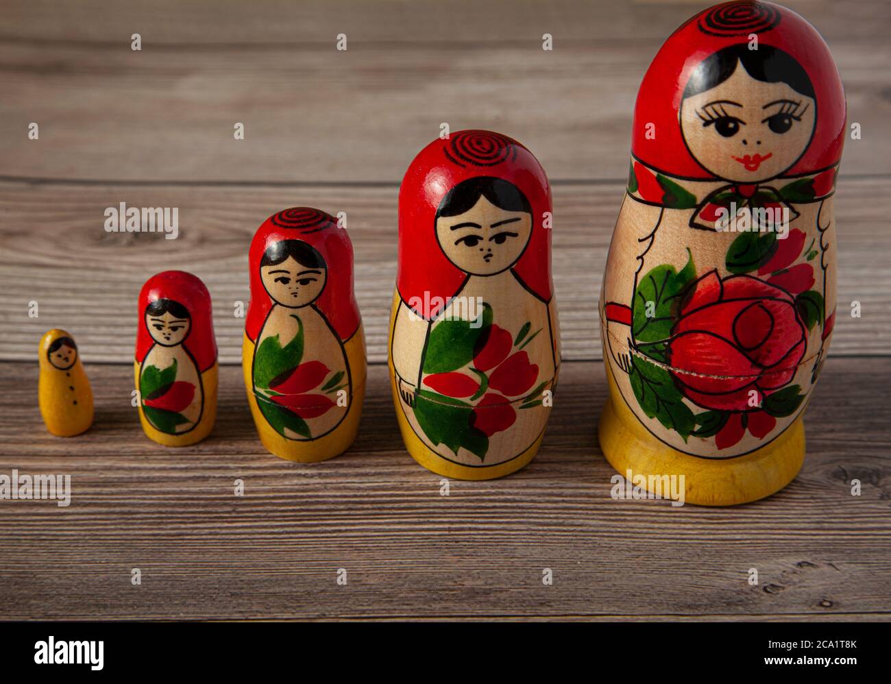 A line up of handmade Russian Matrushka dolls on wooden background. These folkloric women figurines are famous in Slavic countries and these toys are Stock Photo