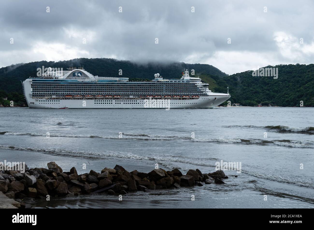 The Crown-class cruise ship 'Ruby Princess' leaving the Port of Santos under rainy overcast sky. View from Luiz La Scalla alderman square. Stock Photo