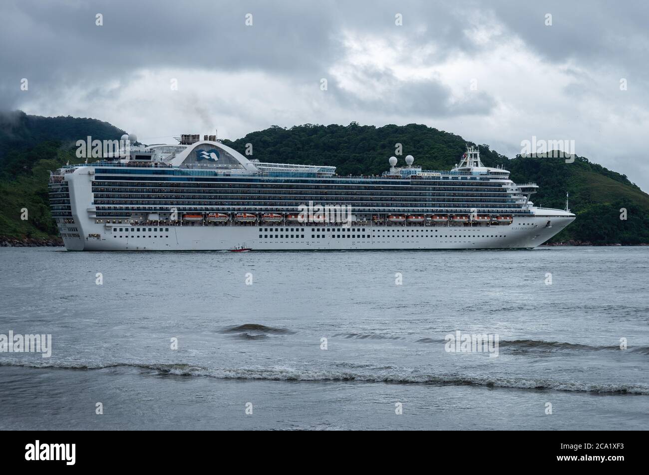 The Crown-class cruise ship 'Ruby Princess' leaving the Port of Santos under rainy overcast sky. View from Luiz La Scalla alderman square. Stock Photo