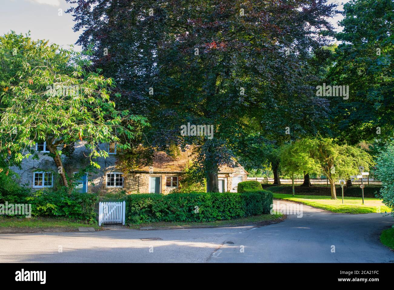 Cottage through trees in the village of Little Haseley, Oxfordshire, England Stock Photo