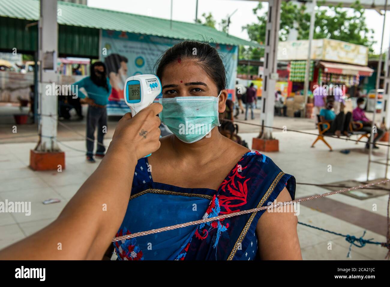 New Delhi, India. 03rd Aug, 2020. A woman wearing a face mask as a preventive measure gets her body temperature checked at the bus depot.Uttar Pradesh Government offers free ride for all women travelling today for Rakshabandhan (Rakhi), while travelling amid Covid-19 period the government arranged thermal screening and hand sanitizer at the Bus Depot as well as inside the buses. Credit: SOPA Images Limited/Alamy Live News Stock Photo