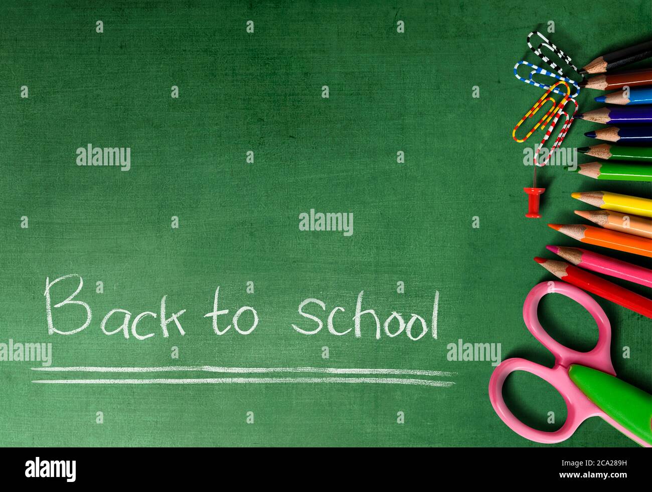 Colored pencils and scissors with a green background. Back to School ...