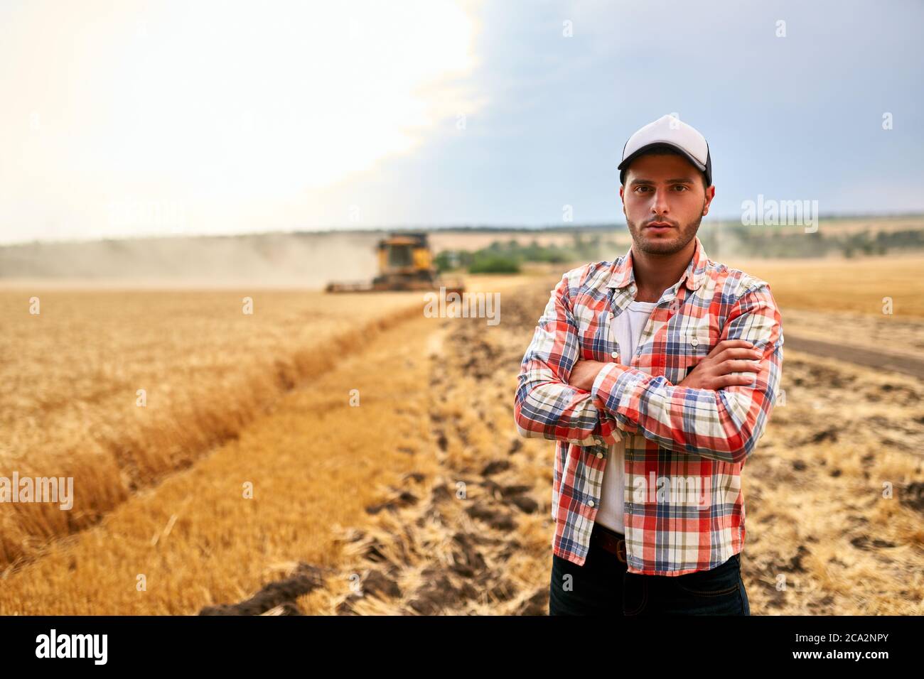 Happy farmer proudly standing in a field with arms crossed on chest ...