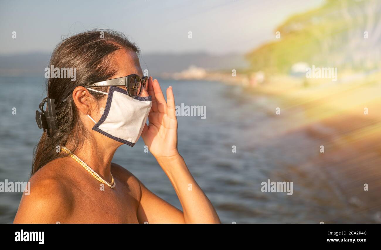 Woman walking on the beach wearing mask in coronavirus times. Stock Photo