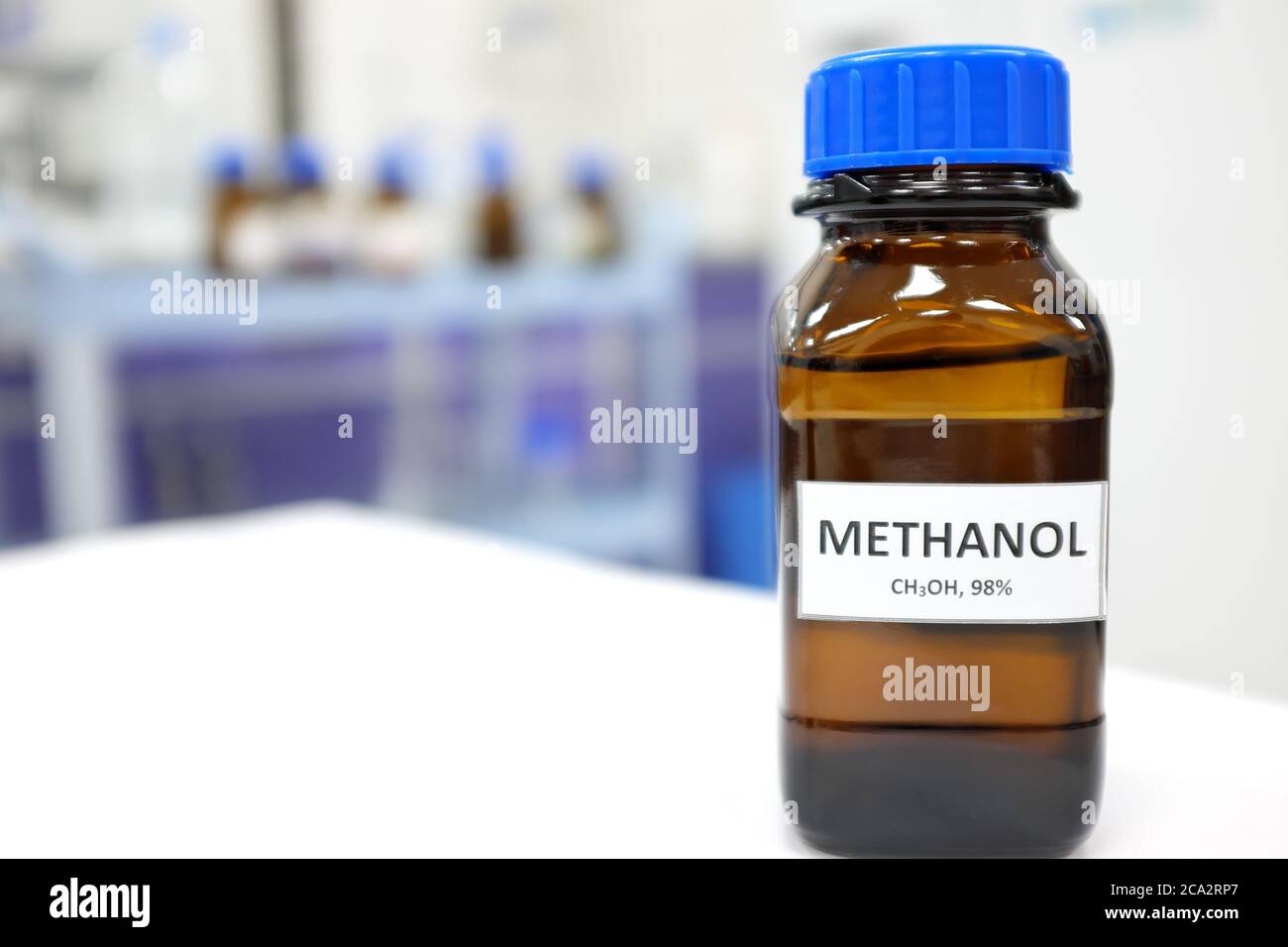 Selective focus of methanol brown amber glass bottle inside a laboratory. Blurred background with copy space. Stock Photo