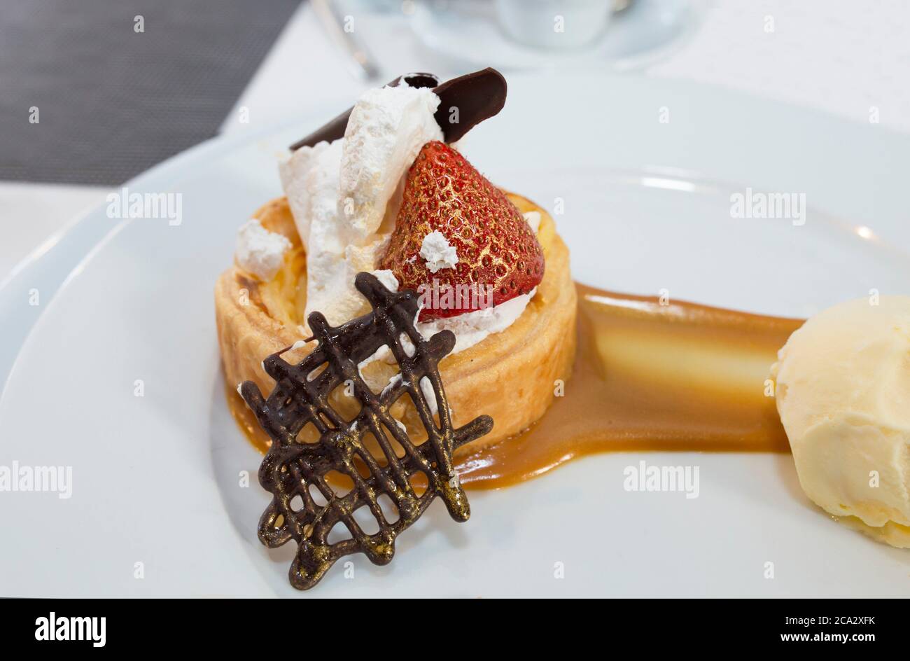 Haute cuisine dessert coated with edible gold dust. Puff pastry filled with creme brulee, raspberry and chocolate tile topped with Madagascar vanilla Stock Photo