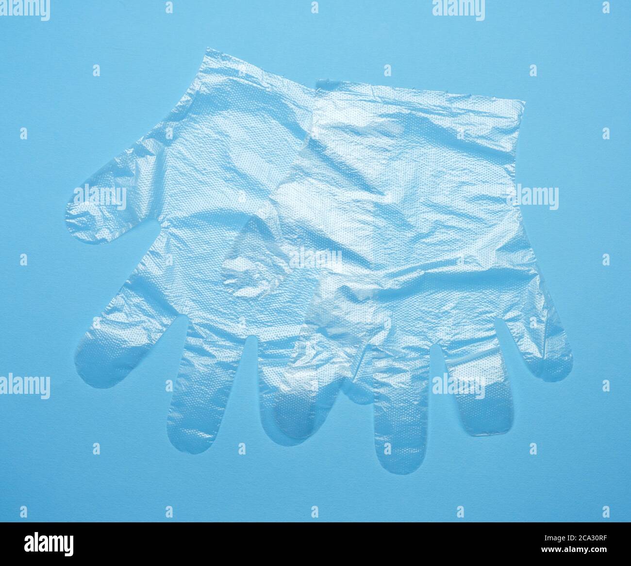 pair of disposable polyethylene gloves on a blue background, top view, flat lay. Stock Photo