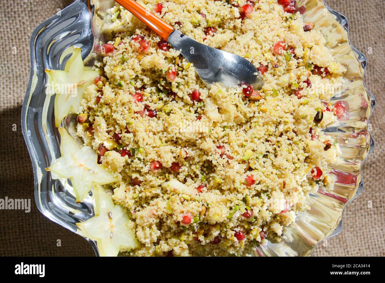 Italian couscous with pomegranate corn pistachios and thinly sliced vegetables. Stock Photo