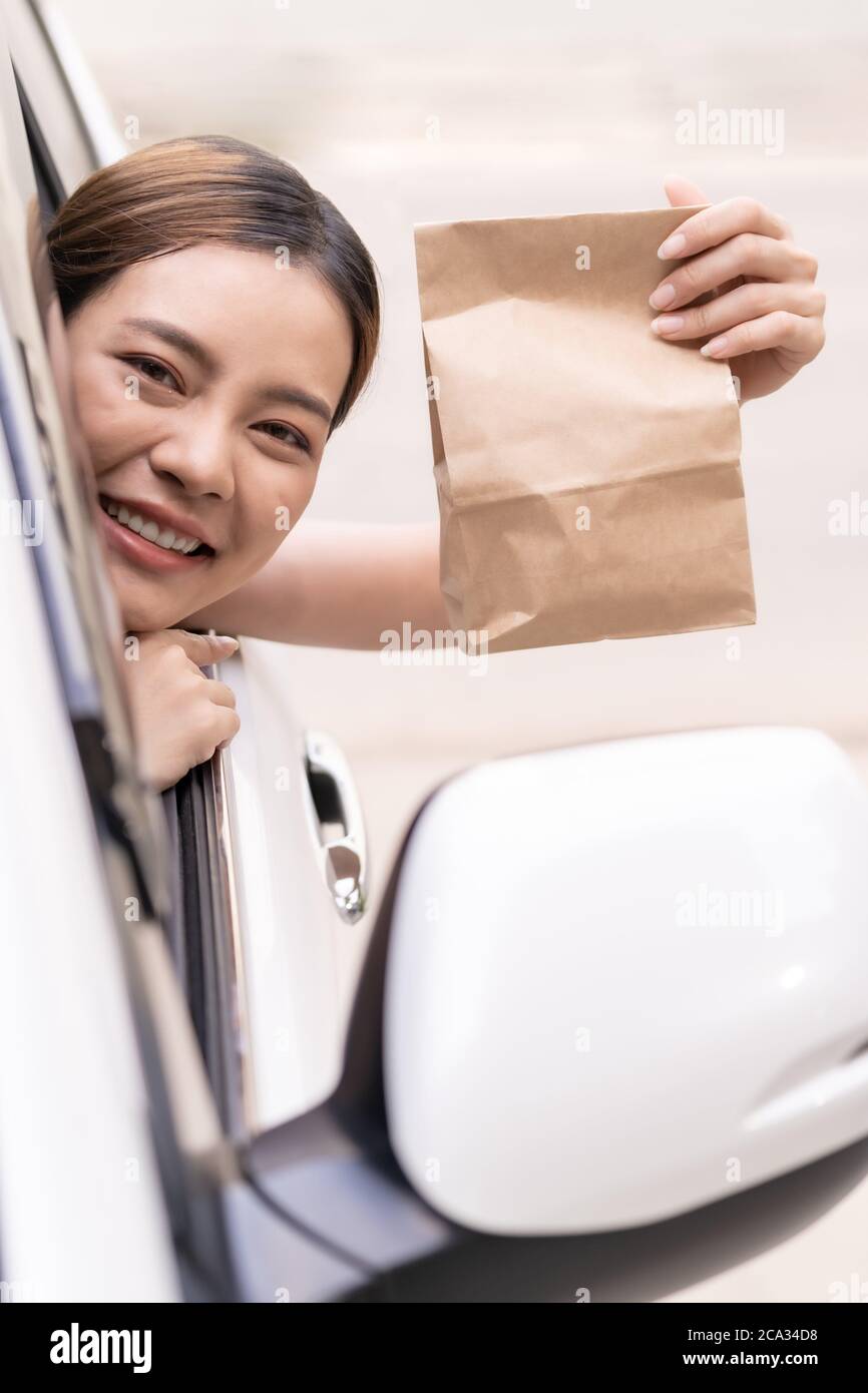 Asian Young Adult In Car Holding Disposable Bag For Take Out Food From asian-young-adult-in-car-holding-disposable-bag-for-take-out-food-from