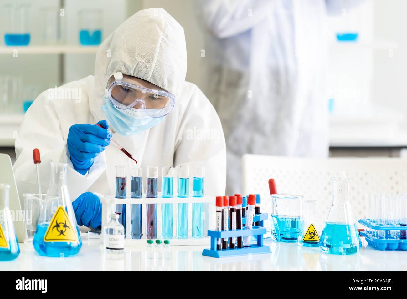 Scientists use dropper to drop blood sample to test tube in tube rack to research and develop vaccine for coronavirus covid-19 pandemic with his Stock Photo