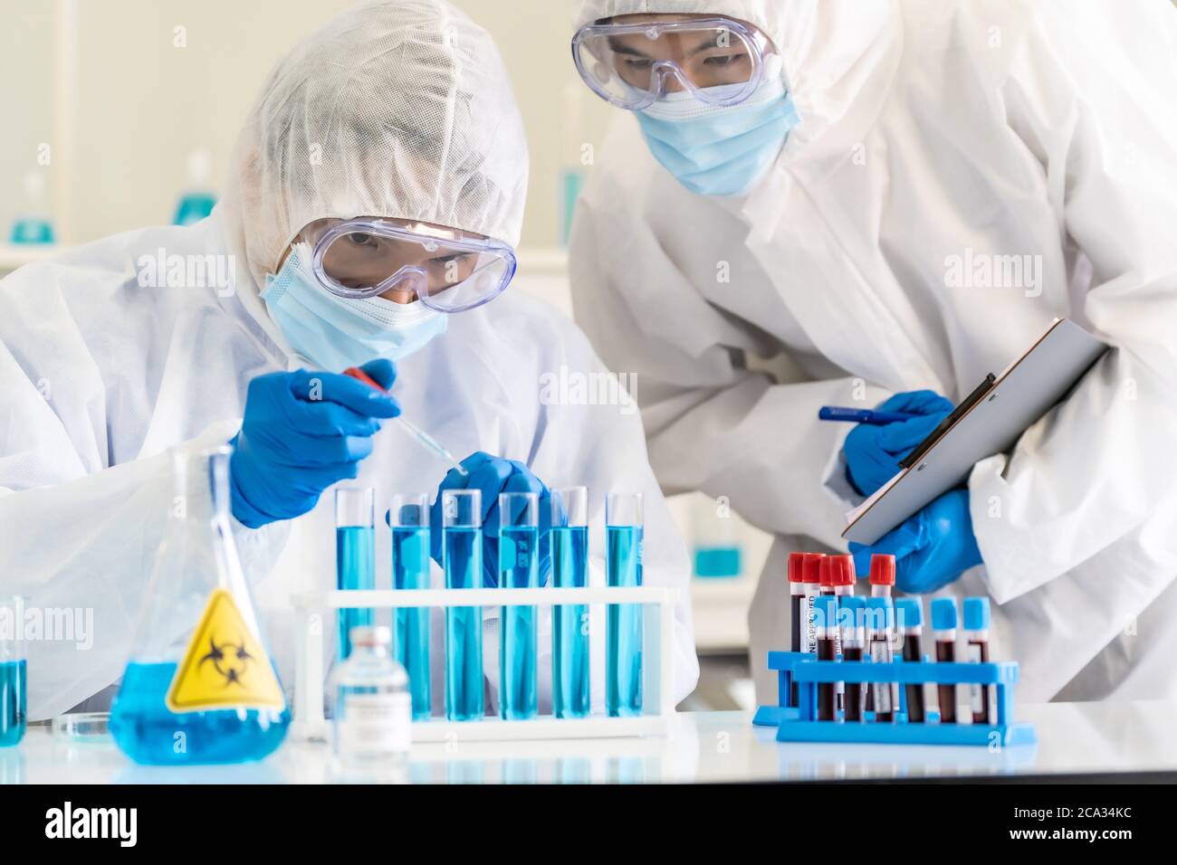 Scientists use dropper to drop chemical reagent to test tube in tube rack to research and develop vaccine for coronavirus covid-19 pandemic with his Stock Photo