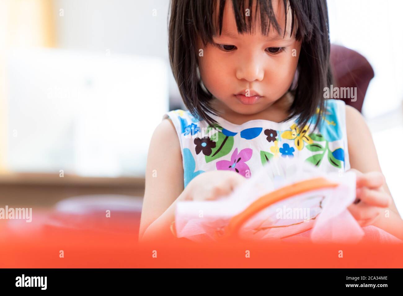 Asian girl child sewing in living room at home as home schooling while city lockdown because of covid-19 pandemic across the world. Home Scholling Stock Photo