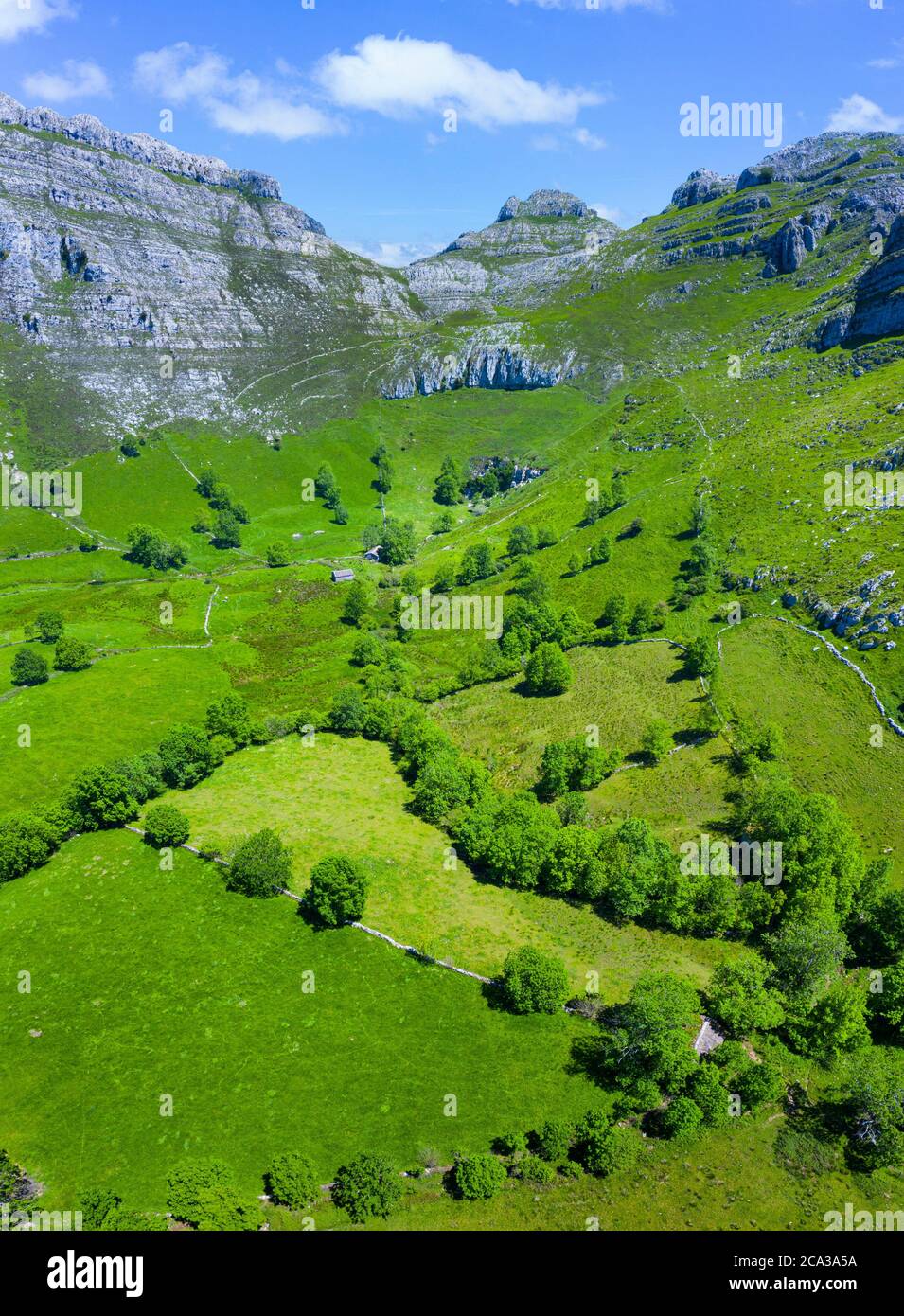 Spring landscape of mountains, meadows of mowing and cabins pasiegas in the Miera Valley, Cantabria, Spain, Europe. Stock Photo