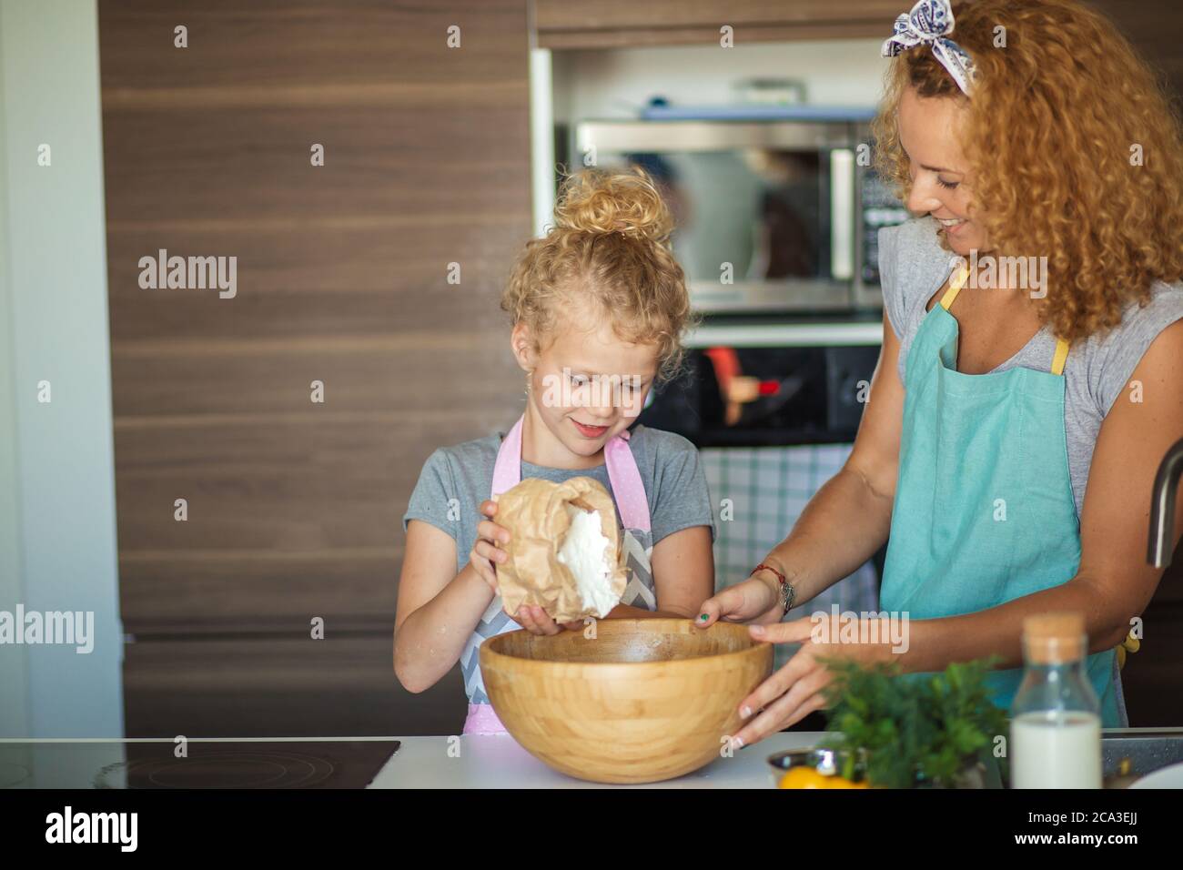 Cute little girl and her beautiful mother are sprinkling flour from ...