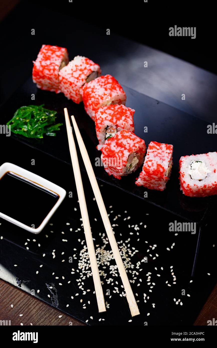 Sushi with salmon. Soy sauce, red caviar. Sushi on a black background. Stock Photo