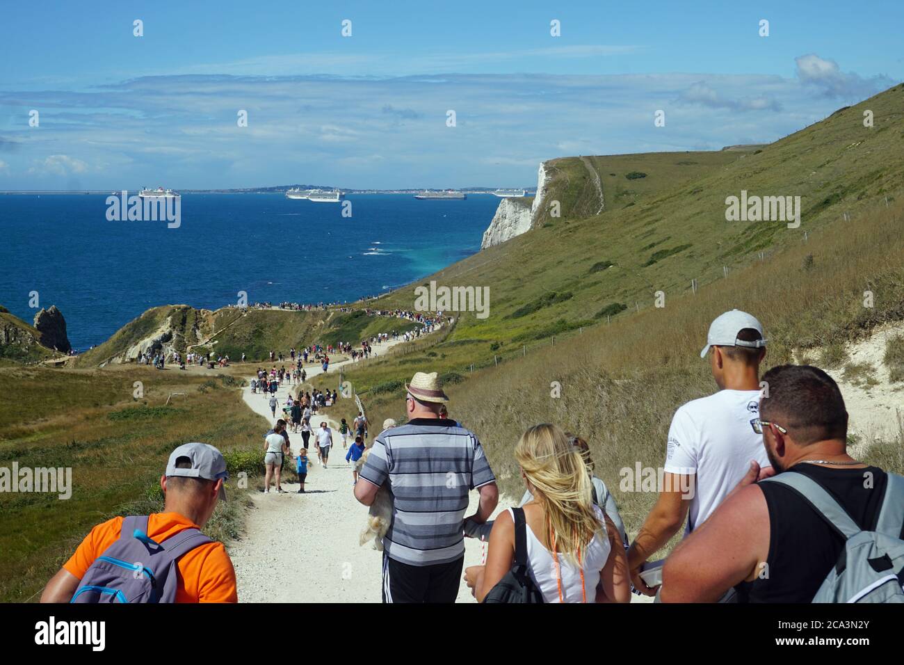 Tourists flock to Durdle Door to enjoy the sunshine and view  with its popular sandy beach and iconic limestone arch, Lulworth Estate, Dorset, UK Stock Photo