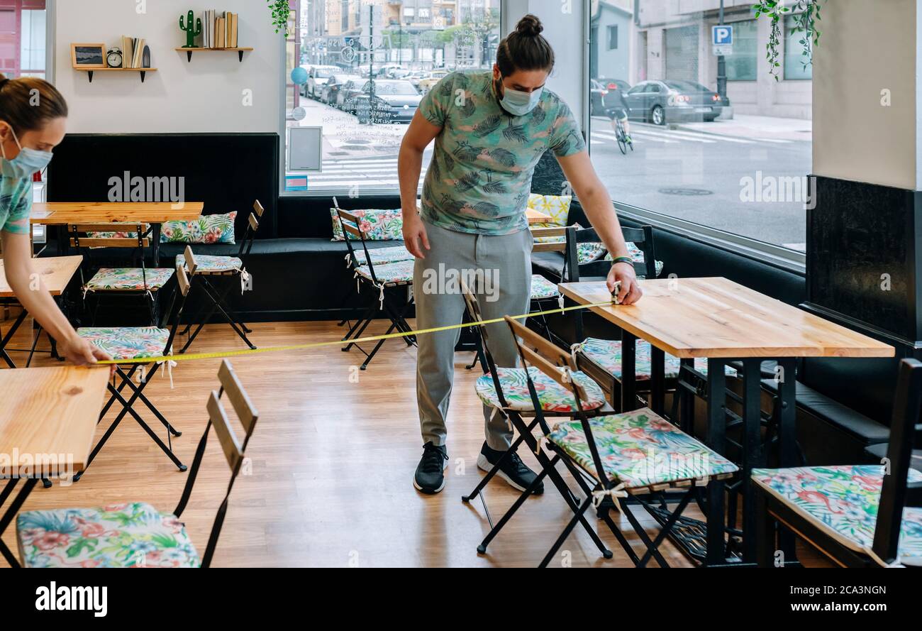 Workers measuring social distance between tables Stock Photo