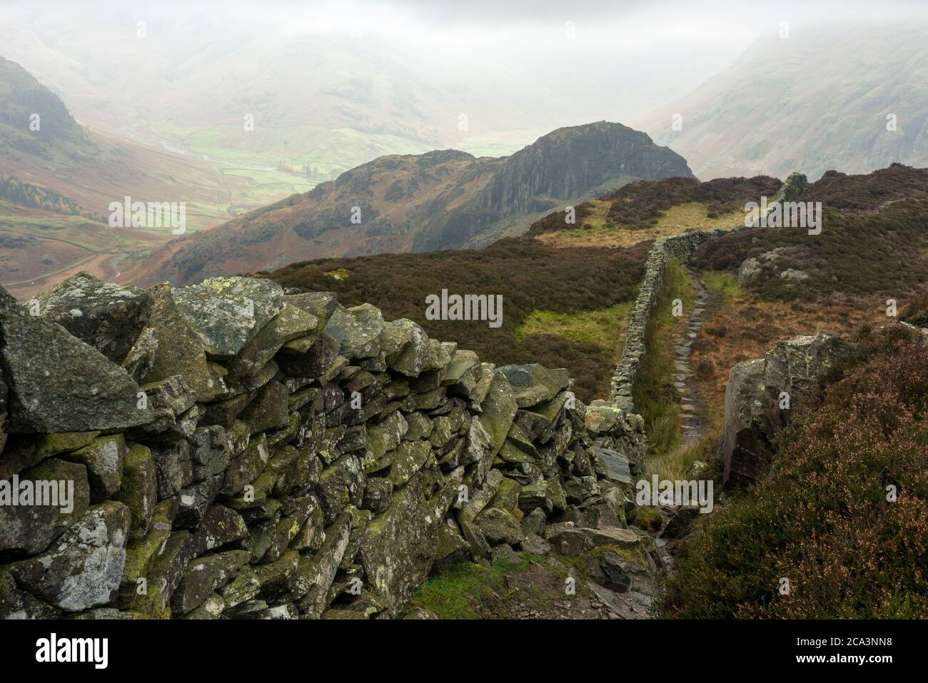 Footpath and dry stone wall on Lingmoor Fell with Side Pike beyond in the Lake District National Park, Cumbria, England. Stock Photo