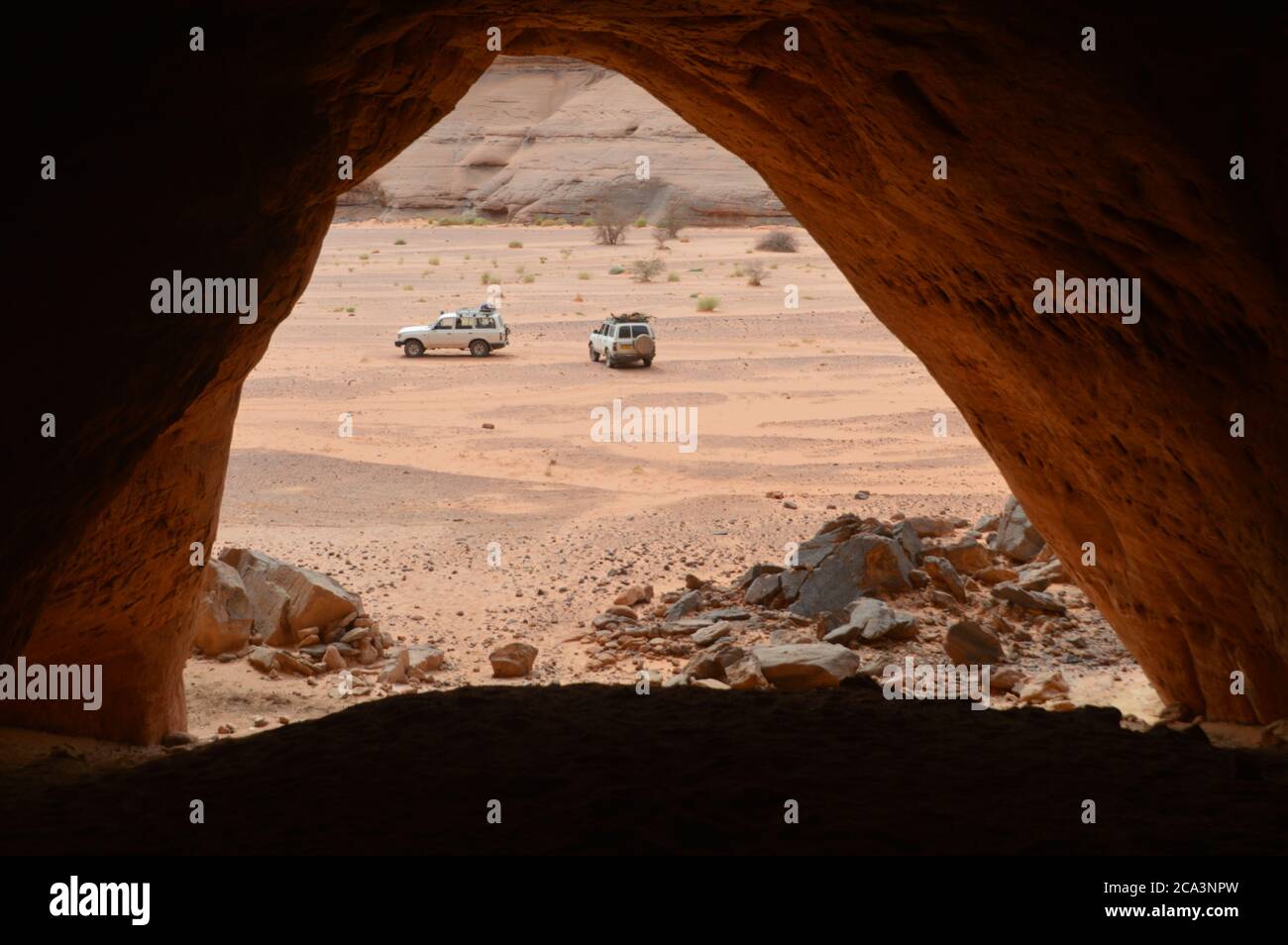 Algeria, Illizi, Tassili N'Ajjer National Park:  view of the expedition cars from the mouth of a large cave at Tidrunag in Wadi In Tehak in the Tadrar Stock Photo