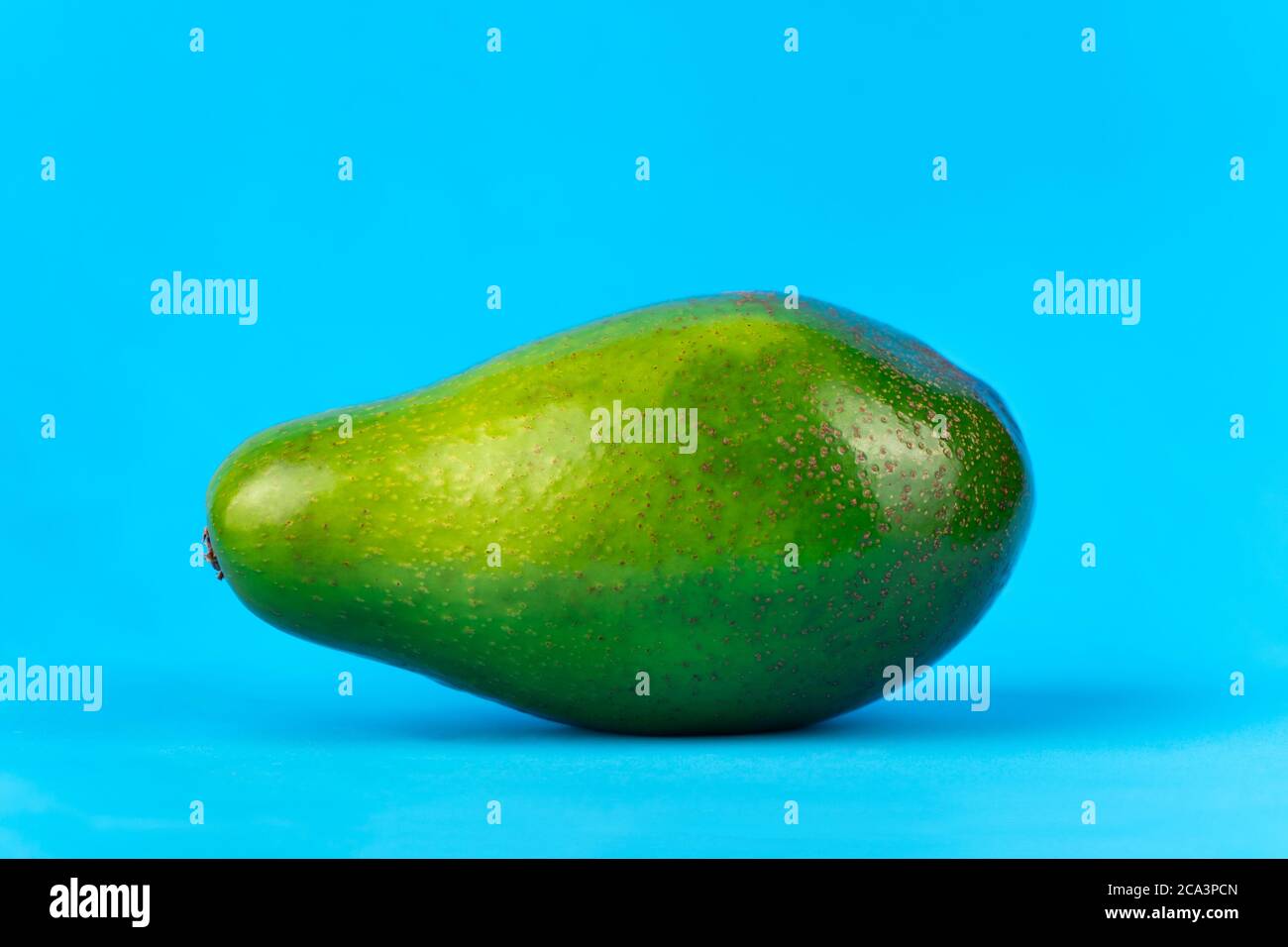 Ripe fresh green avocado on blue background Stock Photo