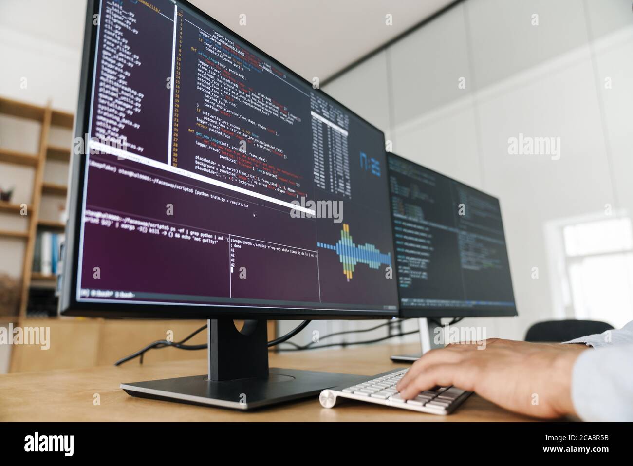 Cropped image of programmer man typing on keyboard while working with computers in office Stock Photo