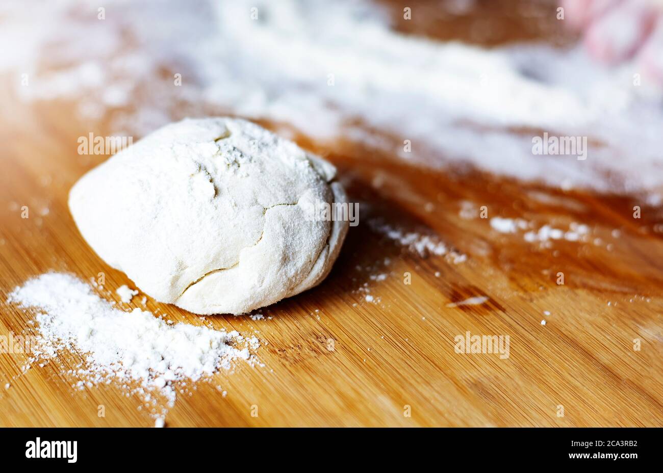 a fresh dough on a floured wooden board. Preparation and ingredients for pizza, bread and pasta. Raw food Stock Photo