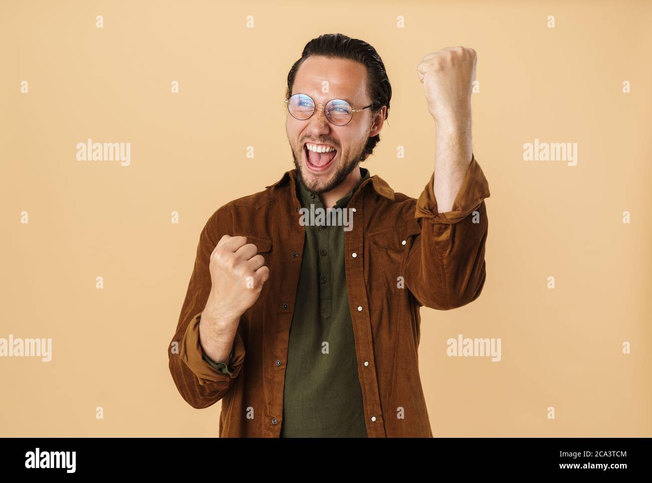 Image of delighted man in eyeglasses making winner gesture and ...