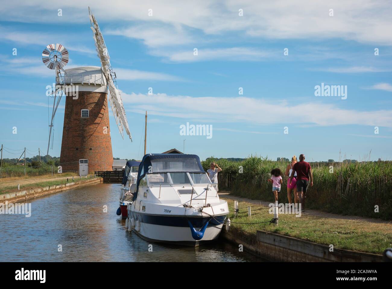 Family holiday UK, rear view of a family group walking towards Horsey windmill in the Norfolk Broads, East Anglia, England, UK Stock Photo