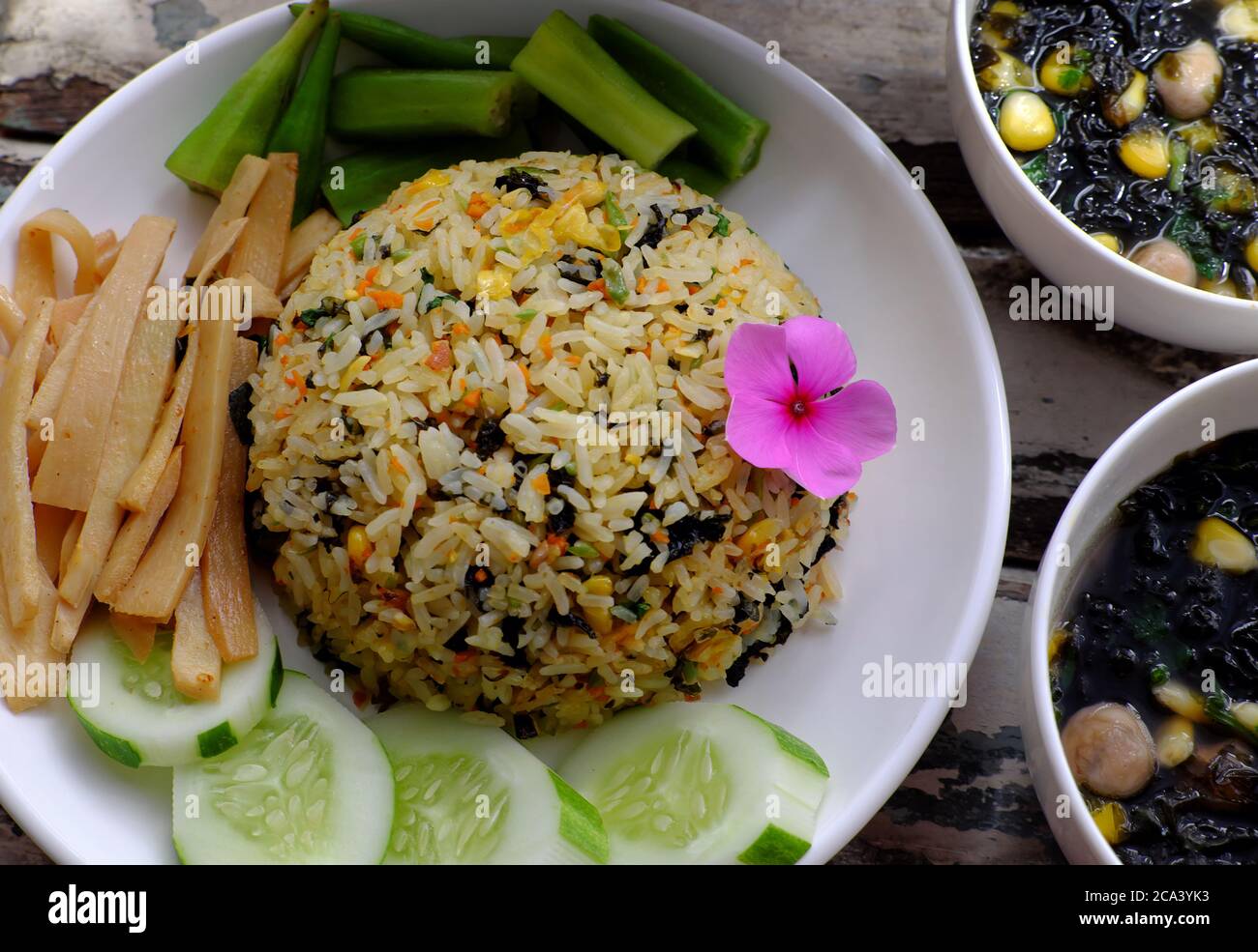 plate of fried rice dish with vegetables, cucumber, bamboo shoot, okra and seaweed soup for family meal lunch, delicious vegan food ready to eat Stock Photo