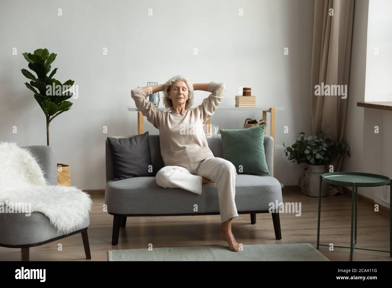 In living room on modern comfy couch relaxing mature woman Stock Photo