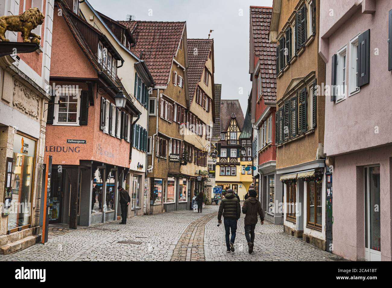 Traditional German half timbered buildings by a quiet medieval cobbled alley or street with shops and few people in Tubingen old town - Germany Stock Photo