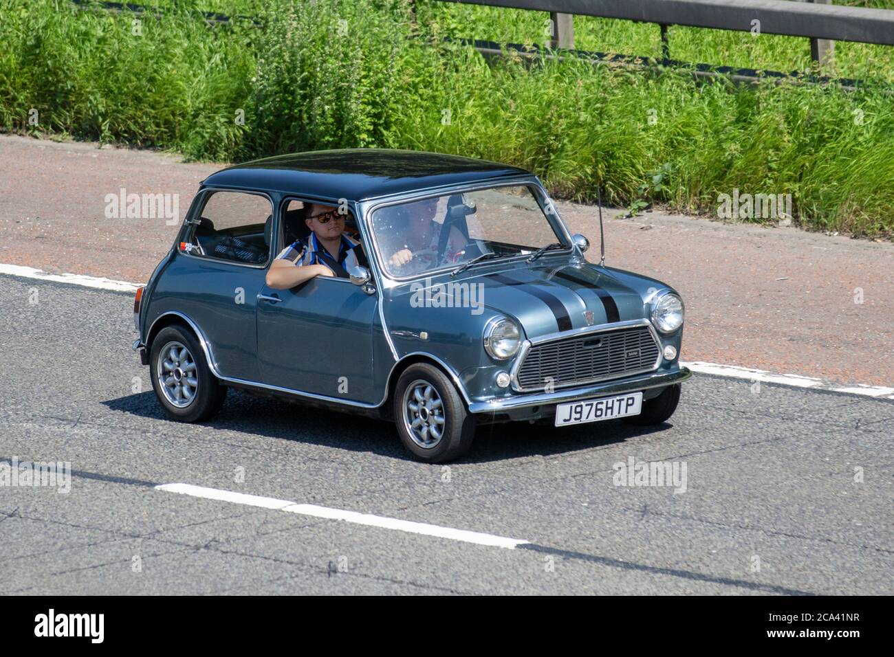 Blue black stripes 1991 Rover Mini Neon; Vehicular traffic moving vehicles, classic cars, cherished veteran, restored old timer, collectible motors, vintage heritage, old preserved, collectable cars driving vehicle on UK roads, motors, motoring on the M6 motorway highway network. Stock Photo