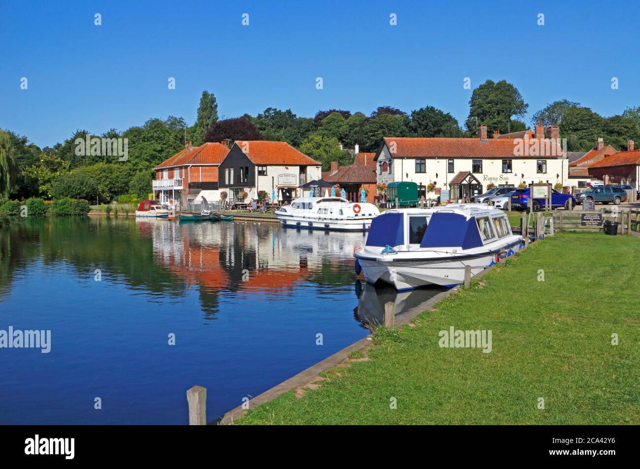 A bend in the River Bure with moored boats by the Rising Sun public house on the Norfolk Broads at Coltishall, Norfolk, England, United Kingdom. Stock Photo