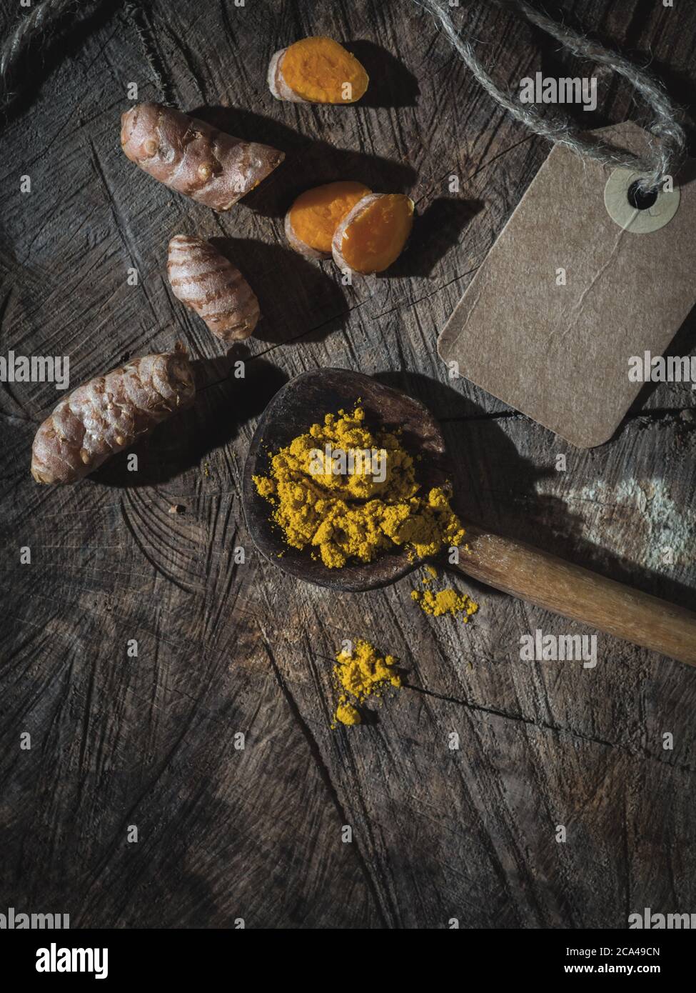 Turmeric (curcumin, Curcuma Longa Linn), powder and rhizome on wooden ladle and vintage wooden table. Overhead shot with copy space. Stock Photo