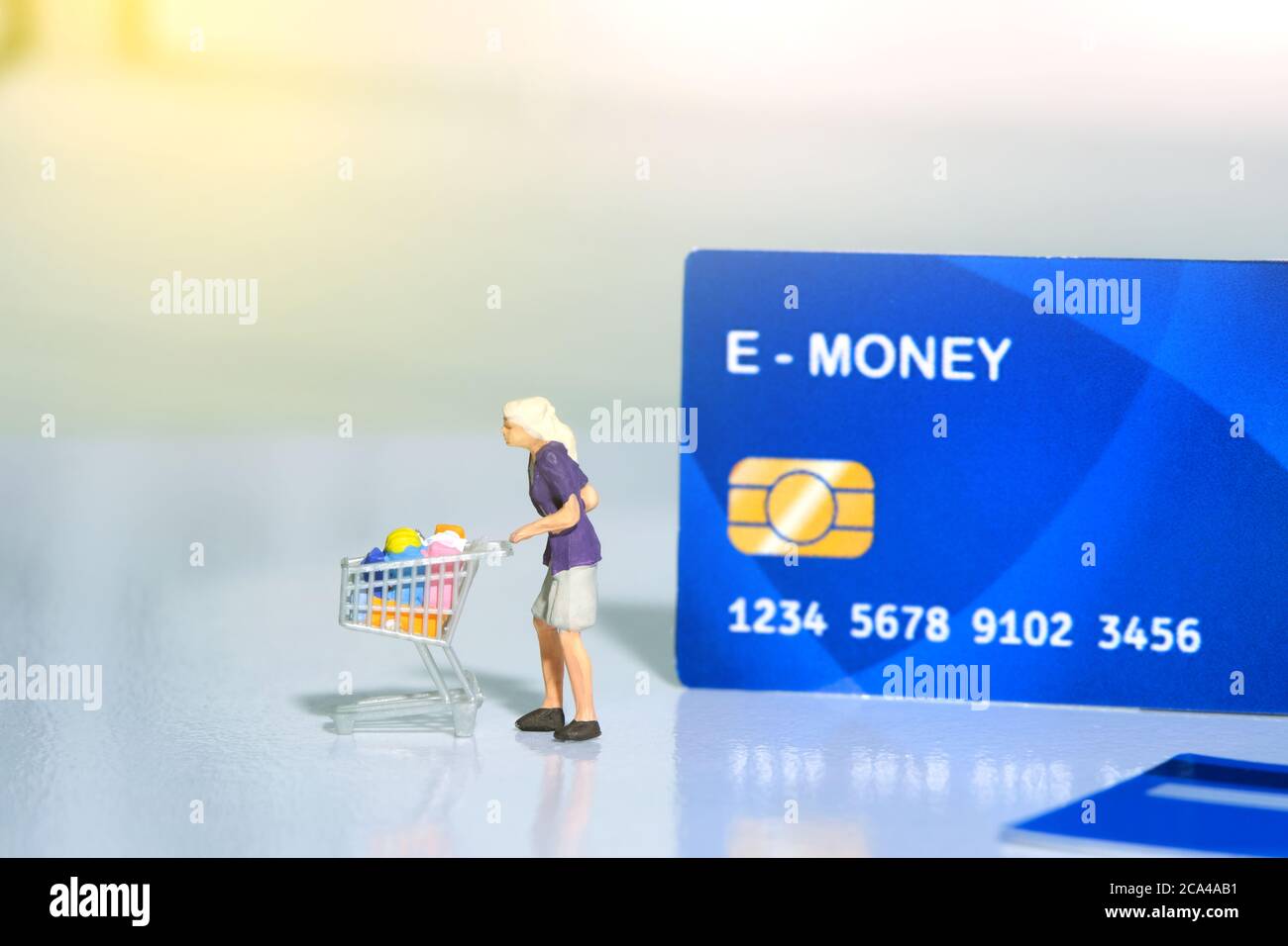 Contact-less payment. Women going shop and pay using electronic money (e-money). Miniature people figurines toys conceptual photography. Stock Photo