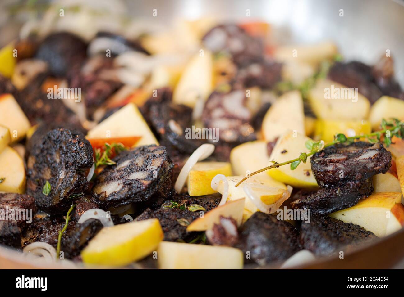 https://c8.alamy.com/comp/2CA4D54/full-frame-slices-of-blood-sausage-and-apples-mixed-with-onions-and-herbs-like-thyme-sizzling-in-large-frying-pan-2CA4D54.jpg