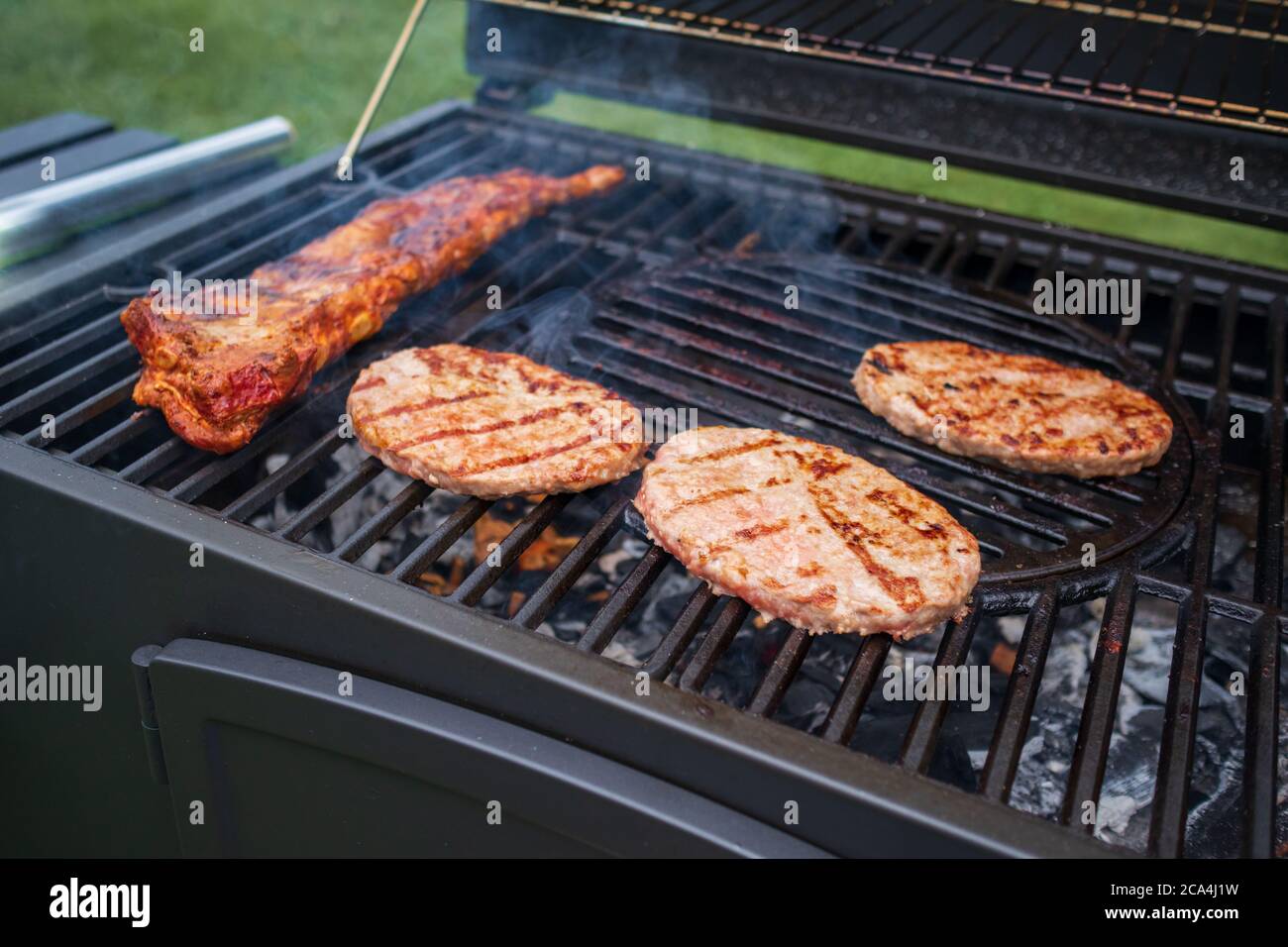 Home barbecue with charcoal in the backyard grilling steaks and other meats for carnivore diet. Stock Photo