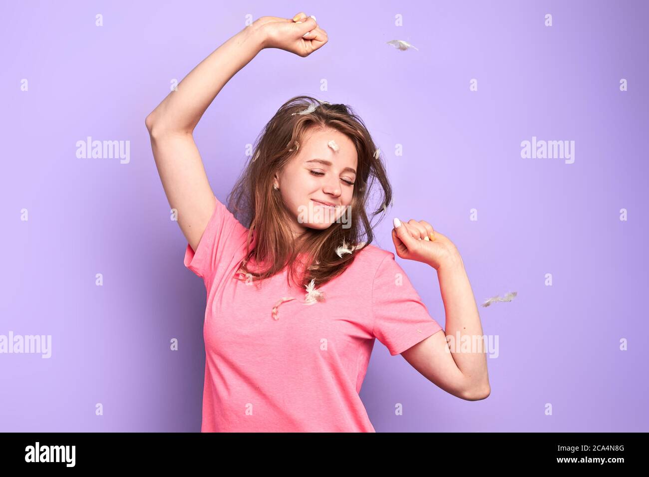 Playful student girl stretches after long sleep, glad to have rest after hard week, has happy smile after pleasant dreams, rejoices having weekend, en Stock Photo