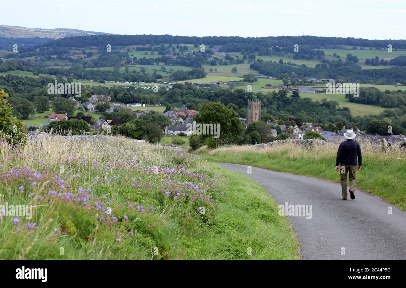 Walker approaching the Peak District village of Youlgrave near Bakewell Stock Photo