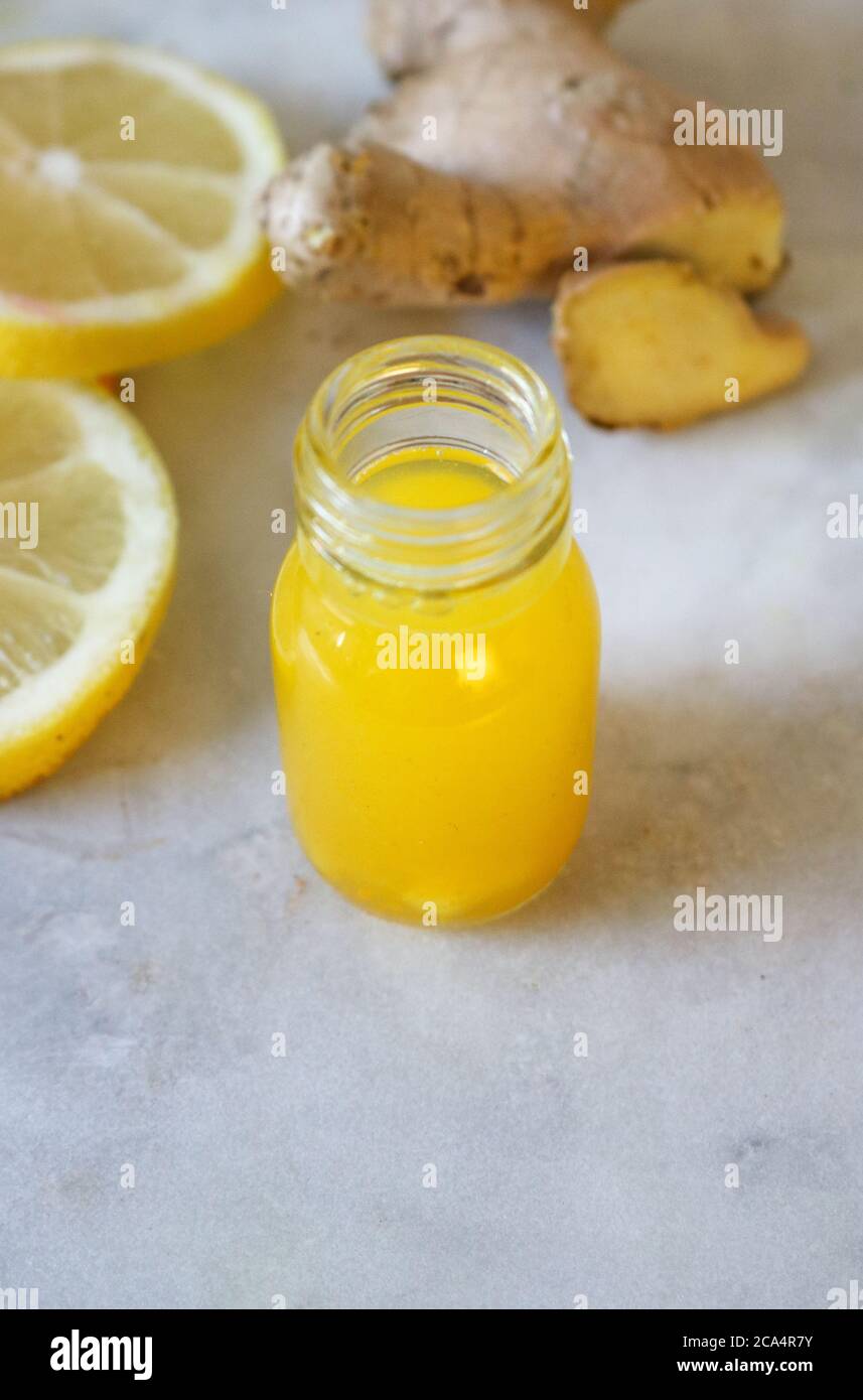 Handmade Turmeric and Ginger and lemon Shot in a small bottle on a marble board Stock Photo