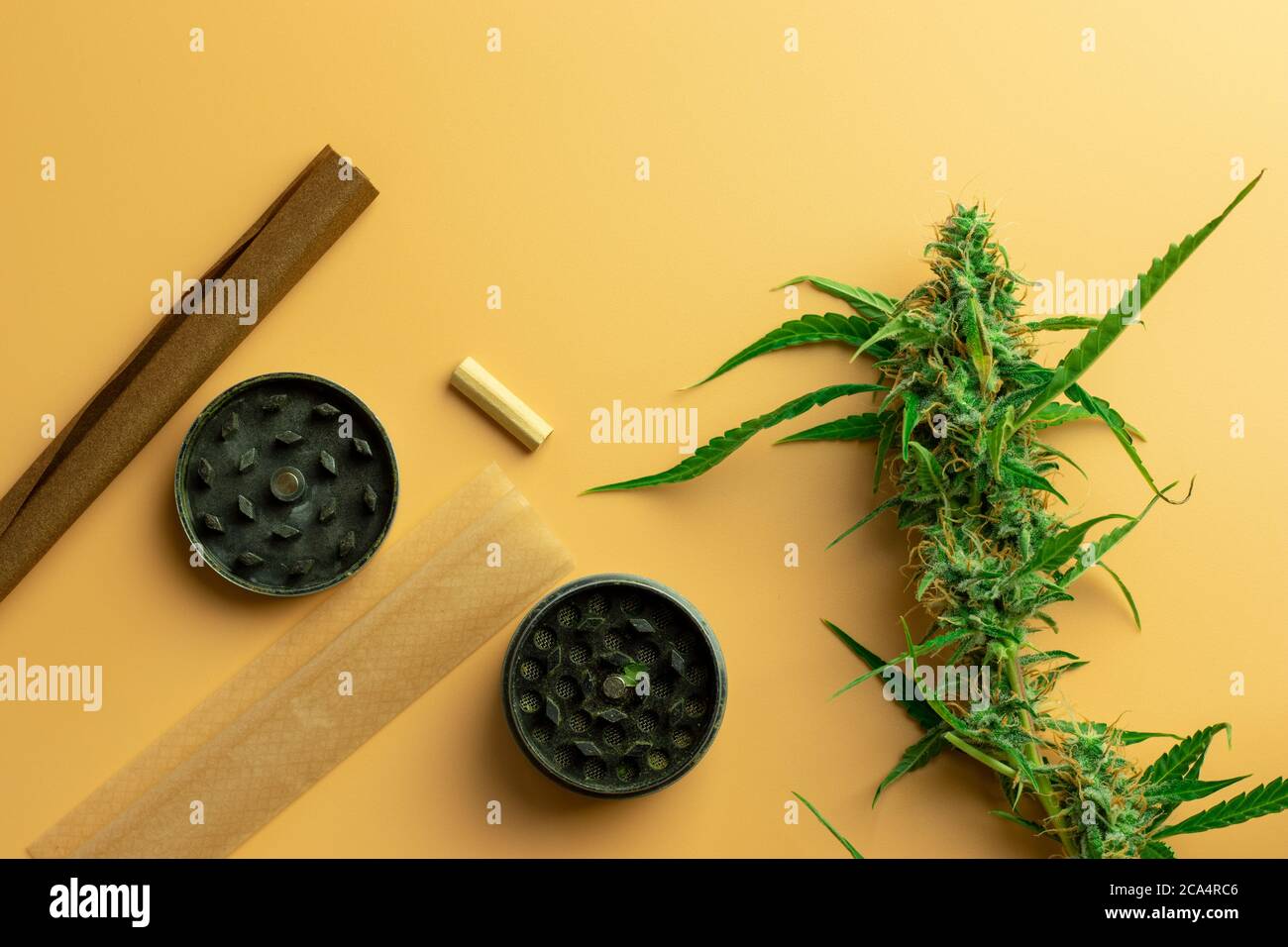 Cannabis and weed industry business. Marijuana accessories use concept. Grinder, paper and blunt with hemp bud on desk Stock Photo