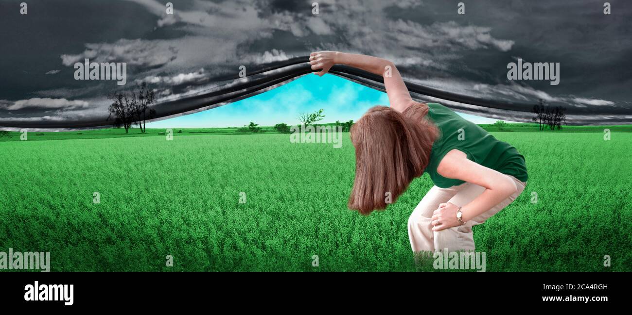 Woman lifting gray sky curtain over the field Stock Photo