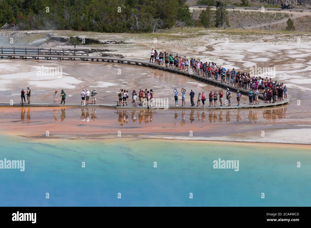 Visitors walk along the boardwalk at Grand Prismatic Spring on Monday, August 3, 2020. Many of the parks boardwalk have been made one-way in order to combat the transmission of the COVID-19 virus. The park recently reported several positive cases of the COVID-19 virus among visitors and concessioners. Stock Photo