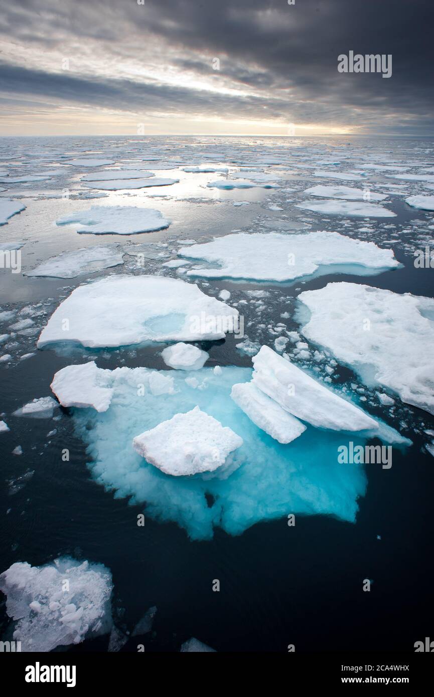 Sea Ice floes in North Arctic with underside visible through surface broken up due to global warming.Viewed from above.Dramatic grey sky  on horizon Stock Photo