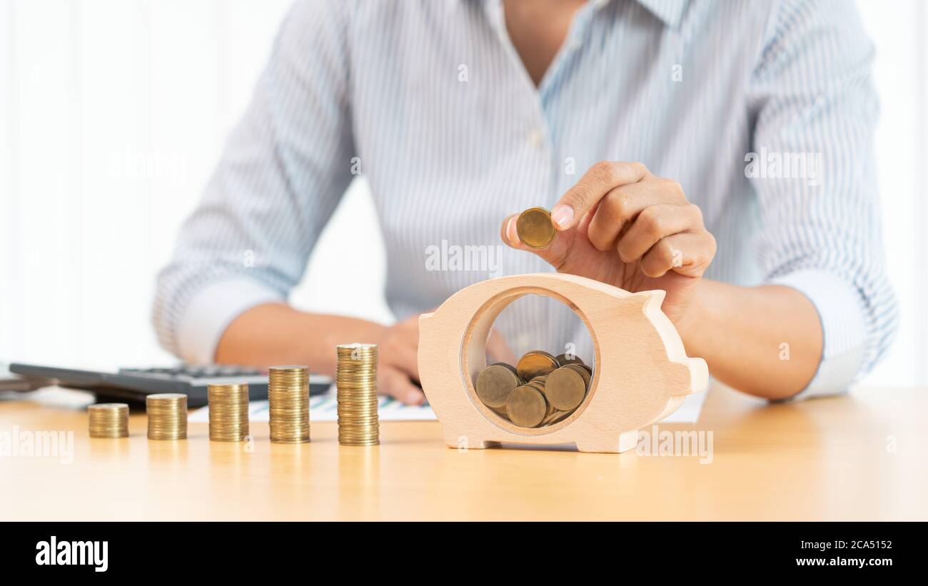 woman hand putting money coin into piggy bank with step of growing ...