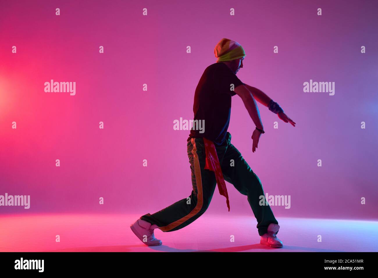 Handsome young professional hip hop dancer performing on stage of dance school, preparing for concert, exercising new movie, training hard in smoky da Stock Photo